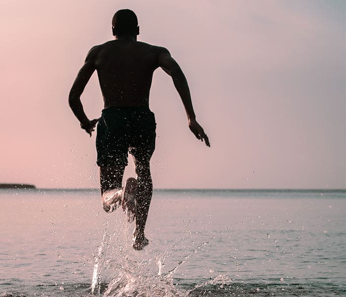 Un hombre dando un salto hacia adelante saltando en una orilla del mar. Haciendo alusión a dar un salto cuántico hacia las estrategias de marketing.marketing
